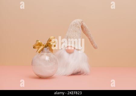 gnome and christmas ball on pink background-modern decorations with white feathers. New Year's gifts Stock Photo