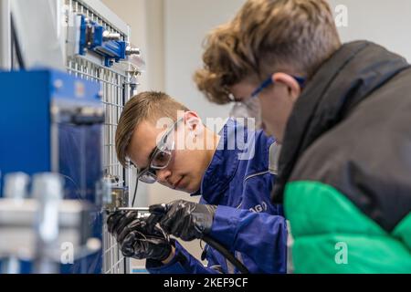 12 November 2022, Brandenburg, Schwarze Pumpe: Marvin Walker (l), a mechatronics technician in his third year of training, shows Hugo Seidel tasks from his training on an experimental wall in the hydraulics cabinet. Lusatia Energie Bergbau AG and Lusatia Energie Kraftwerke AG (LEAG) are holding an open day at the Schwarze Pumpe industrial park, where interested parties can look over the shoulders of trainees and instructors. LEAG is looking to fill 100 vacancies in industrial-technical and commercial apprenticeships as well as in two dual study programs. Photo: Frank Hammerschmidt/dpa Stock Photo