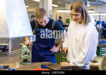 12 November 2022, Brandenburg, Schwarze Pumpe: Lukas Franz (r) is interested in a technical apprenticeship and is trying his hand at making marks in metal in the metalworking training workshop. He is being guided by Julian Klitten, a first-year mechatronics technician. Lusatia Energie Bergbau AG and Lusatia Energie Kraftwerke AG (LEAG) are holding an open day at the Schwarze Pumpe industrial park, where interested parties can look over the shoulders of trainees and instructors. LEAG is looking to fill 100 vacancies in industrial-technical and commercial apprenticeships as well as in two dual s Stock Photo