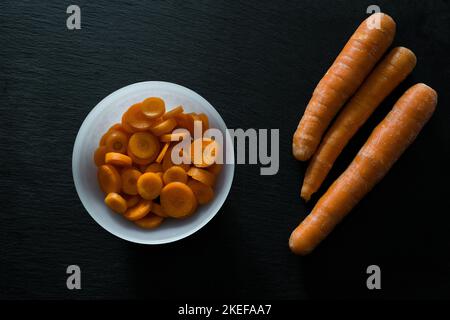 Sliced carrots in a bowl on black background Stock Photo