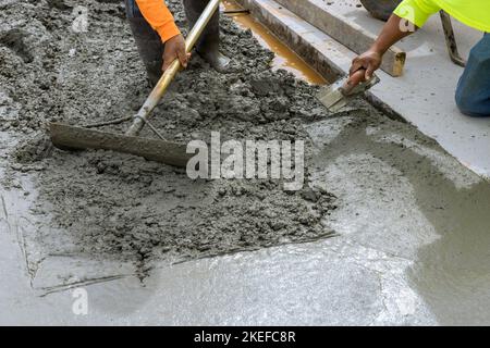 Construction worker pouring cement to create new sidewalk on side of house Stock Photo