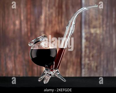 unusual red wine glass in pipe shape on wooden background, special funny gift for wine lovers Stock Photo