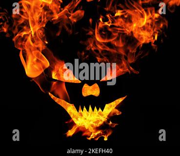 Burning scary halloween face, evil laughing devil face with flames isolated on black background Stock Photo