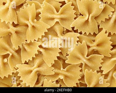 Close-up of dry uncooked Italian pasta farfalle, background of pasta in butterfly shape Stock Photo