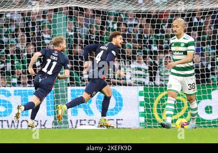 Ross County's David Cancola (centre) celebrates scoring their side's first goal of the game from the penalty area as Celtic's Daizen Maeda (right) looks dejected during the cinch Premiership match at Celtic Park, Glasgow. Picture date: Saturday November 12, 2022. Stock Photo