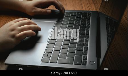 Side view of woman hands using laptop on vintage wood desk. Business, finance and gaming concept. Work from home. Workplace. Stock Photo