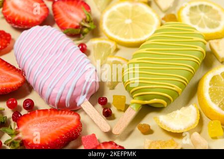 Two ice creams on a sticks - strawberry and lemon on a beige background. Summer fruit desserts. Stock Photo