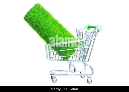 Roll of artificial grass in a toy shopping trolley isolated on white background. Stock Photo