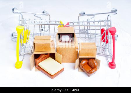 Unpacked tiny delivery boxes with miniature furniture figurines by small push trolleys isolated on white background. Renting furniture for a new apart Stock Photo