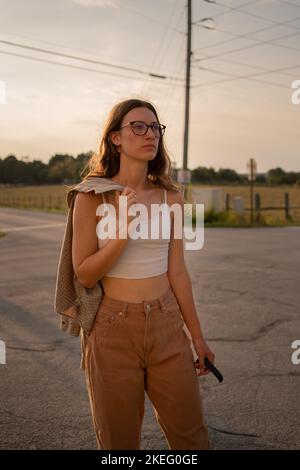 A vertical shot of a fashionable young Caucasian female walking in a street Stock Photo