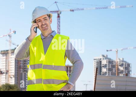 Professional builder standing with a notebook in front of the construction site Stock Photo