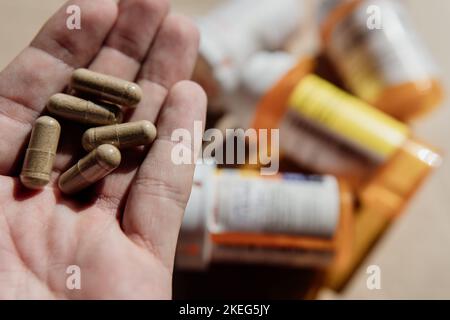 Tablets, capsules, antibiotics. Disease prevention. Treatment for colds and flu. Coronavirus. Receptor drugs. White and green pills. Pills in a man's Stock Photo