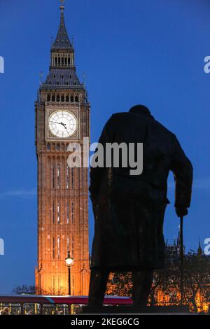 London, UK. 12th Nov, 2022. The iconic Elizabeth Tower, the clock tower also commonly known as Big Ben at Houses of Parliament stands illuminated against the clear blue sky with the Winston Churchill Statue on Parliament Square right across. An unusually warm and sunny November Day comes to a close in Westminster, London. Credit: Imageplotter/Alamy Live News Stock Photo