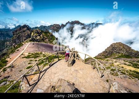 Description: Sporty woman enjoying the fabulous view on Pico Ruivo from the viewpoint on Pico do Ariero in the afternoon. Verade do Pico Ruivo, Madeir Stock Photo