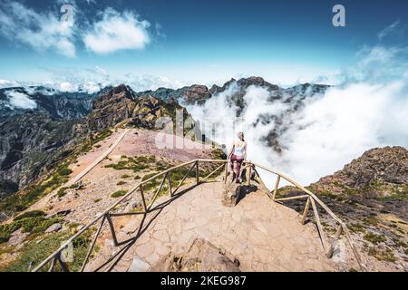 Description: Sporty woman enjoying the fabulous view on Pico Ruivo from the viewpoint on Pico do Ariero in the afternoon. Verade do Pico Ruivo, Madeir Stock Photo