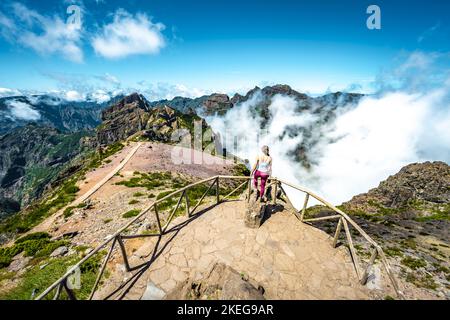 Description: Sporty woman enjoying the fabulous view on Pico Ruivo from the viewpoint on Pico do Ariero in the afternoon. Verade do Pico Ruivo, Madeir Stock Photo