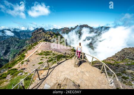 Description: Sporty woman enjoying the fabulous view on Pico Ruivo from the viewpoint on Pico do Ariero in the afternoon. Verade do Pico Ruivo, Madeir Stock Photo