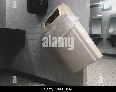 Wall-Mounted Garbage Pail knocked on Angle in Public Bathroom Stock Photo