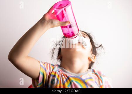 Little girl drinking water from rised bottle Stock Photo