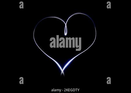Light heart symbol on isloted black background. Long exposure creative photography. Light painting. Love and romance emblem. Glowing and bright effect Stock Photo