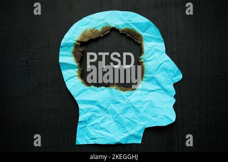 A paper head burned inside and an inscription PTSD. Stock Photo