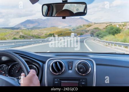 View of the motorway and a landscape of mountains from inside a travelling car. Stock Photo