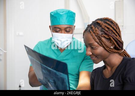 An african dentist shows the x-rays to his patient during a visit. Stock Photo