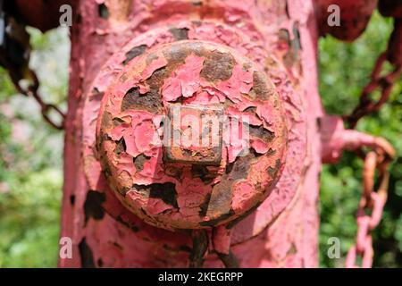 peeling red paint off old antique fire hydrant. Close up of the valve Stock Photo