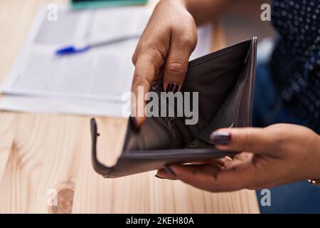 African american woman ecommerce business worker showing empty wallet at office Stock Photo