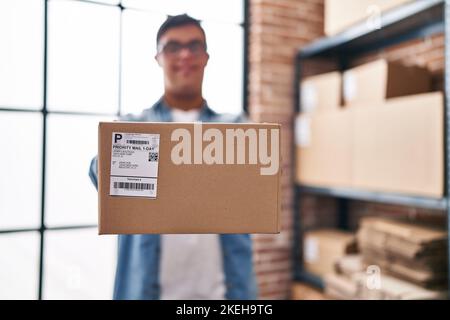 Down syndrome man ecommerce business worker holding package at office Stock Photo