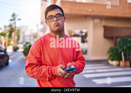 Down syndrome man using smartphone with serious expression at street Stock Photo