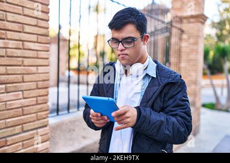 Down syndrome man wearing headphones using touchpad at street Stock Photo