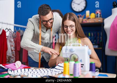 Man and woman tailors smiling confident using sewing machine at clothing factory Stock Photo