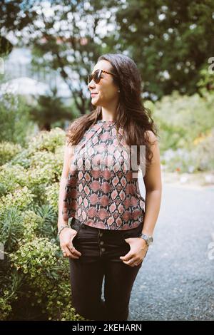 Beautiful young happy multiracial Japanese woman in jeans and shirt in summer park, smiling Stock Photo