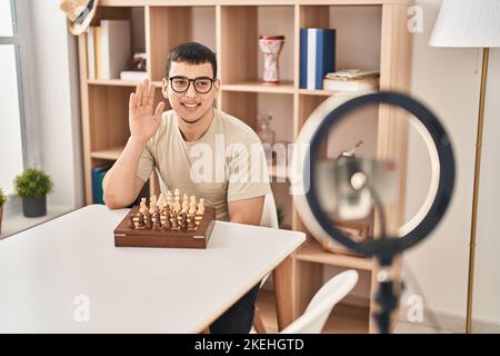Young arab man doing chess tutorial looking positive and happy standing and smiling with a confident smile showing teeth Stock Photo