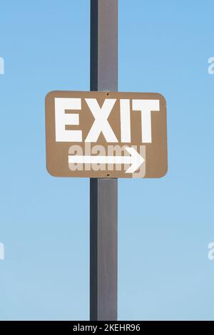 Brown exit sign attached to a post against blue sky background. Business concept. Stock Photo