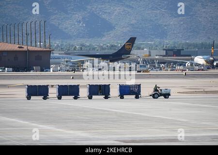 Phoenix, Arizona, USA - November 4, 2022: Baggage tractor hauling luggage across the airport tarmac. Stock Photo