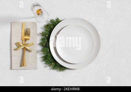 Christmas table setting with empty plate, golden cutlery and a glass on a gray background. Happy new year. Space for text. Winter concept. Top view, f Stock Photo