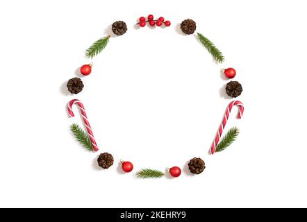Christmas round frame with fir branches, cones, baubles and lollipops isolated on a white background. New Year wreath. Copy space, top view, flat lay. Stock Photo