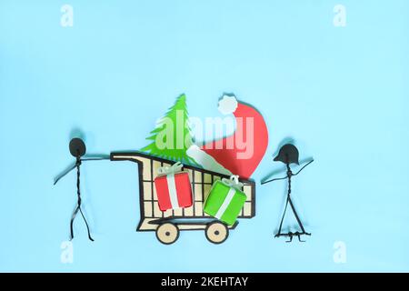 Happy Christmas shopping concept. Couple stick figure pushing a shopping cart with Christmas gifts flat lay composition. Stock Photo