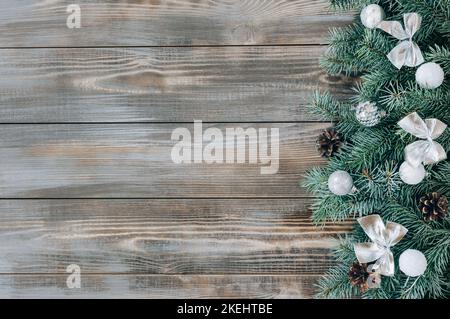Christmas decorations with silver bows and baubles, cones and fir branches on a wooden background. New Year border. Winter concept. View from above. S Stock Photo