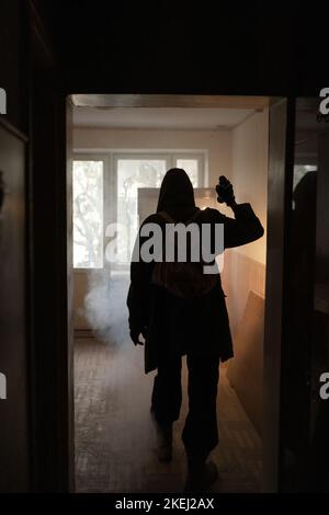 woman against the background of a window in a ruined house and shining flashlight, horror, fear concept, radiation stalker in Chernobyl zombie apocaly Stock Photo