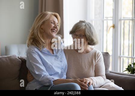 Laughing middle-aged woman enjoy talk with older mother Stock Photo