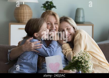 Grandma holding flowers and postcard enjoy congrats from loving family Stock Photo