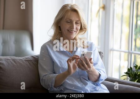 Attractive middle-aged woman using smart phone at home Stock Photo