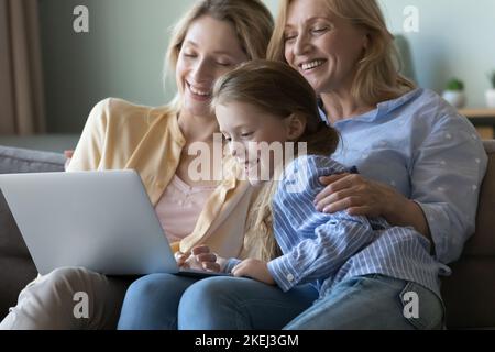 Little girl with mother and grandmother watch movie on laptop Stock Photo