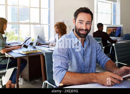 Giving my career the best Ive got. Portrait of a man using a digital tablet at his desk in a modern office. Stock Photo