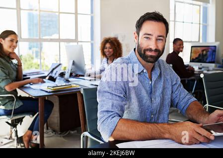 Were all set on success. Portrait of a man using a digital tablet at his desk in a modern office. Stock Photo