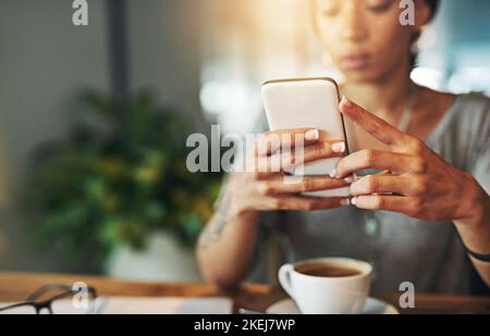 Doing business on the go. a young woman sending an sms while working late in her office. Stock Photo