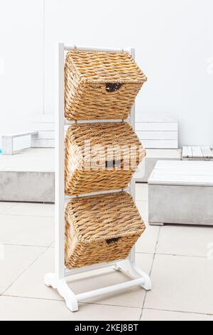 white wooden basket shelf stand with three decorative storage bins in sunny day outdoor Stock Photo